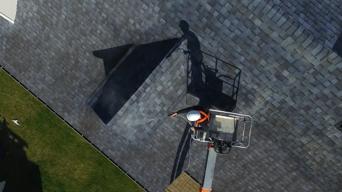 Home with an asphalt-shingle roof showing gradual color fading across sun-exposed slopes