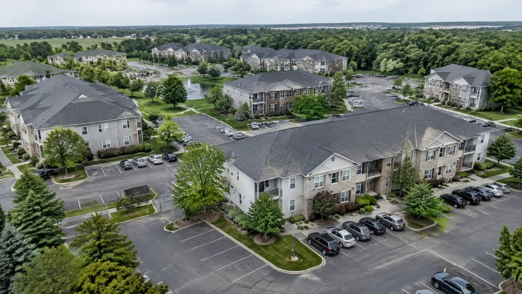 Multifamily apartment property with multiple pitched shingle roofs and landscaped grounds