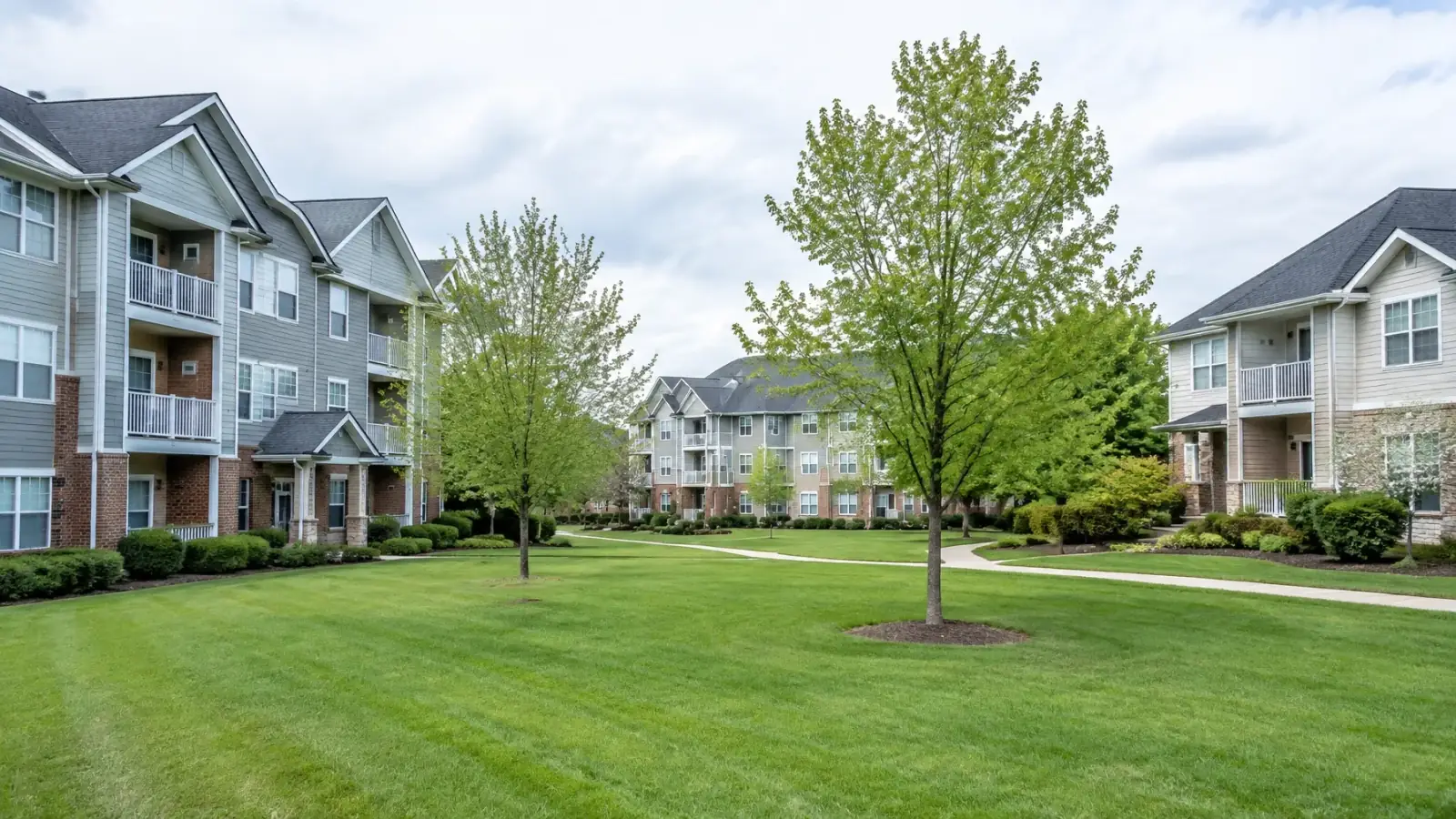 Aerial view of a multifamily residential community with visible pitched asphalt-shingle roofs
