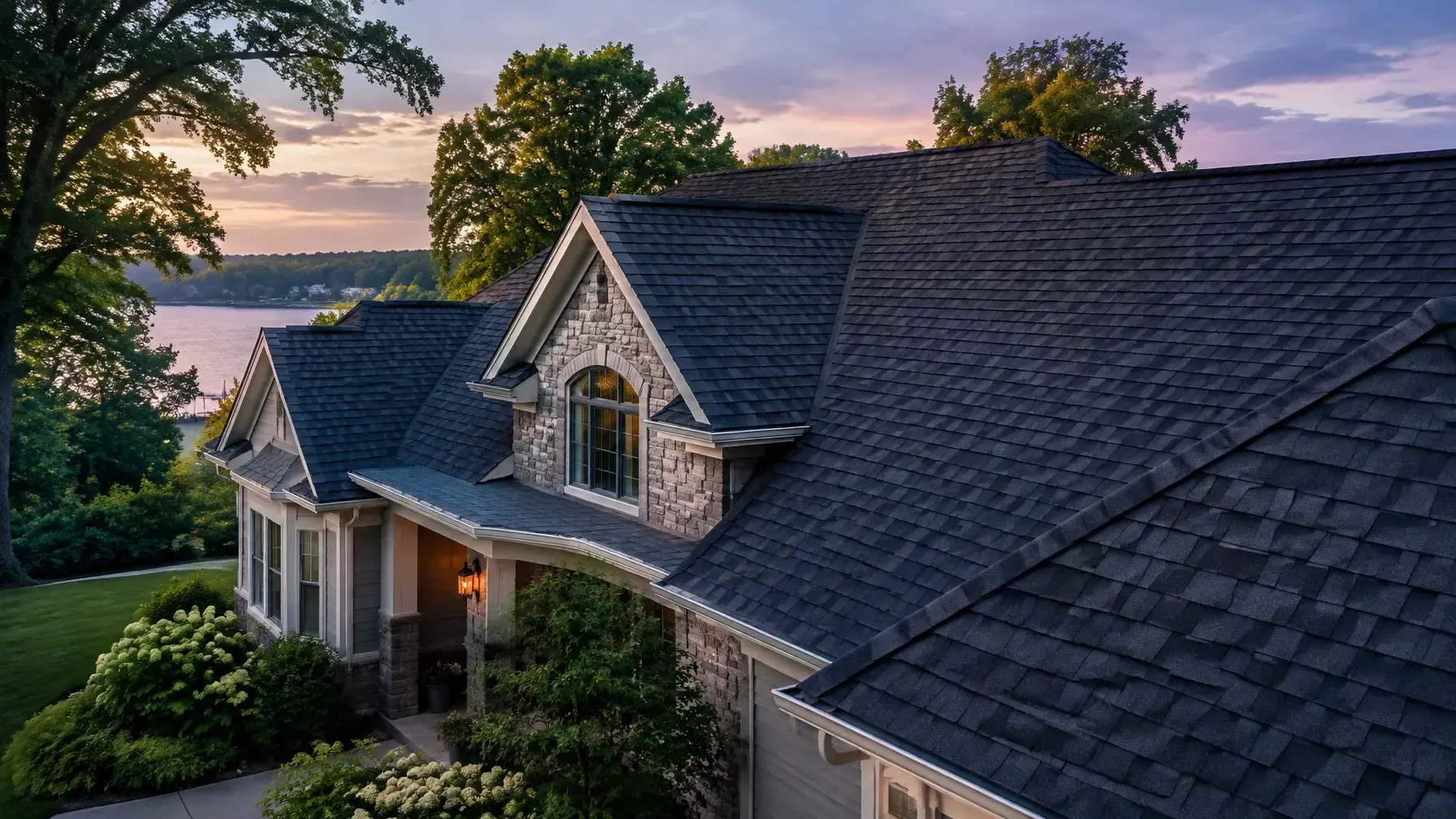 A Michigan home with a charcoal asphalt-shingle roof in late-afternoon light