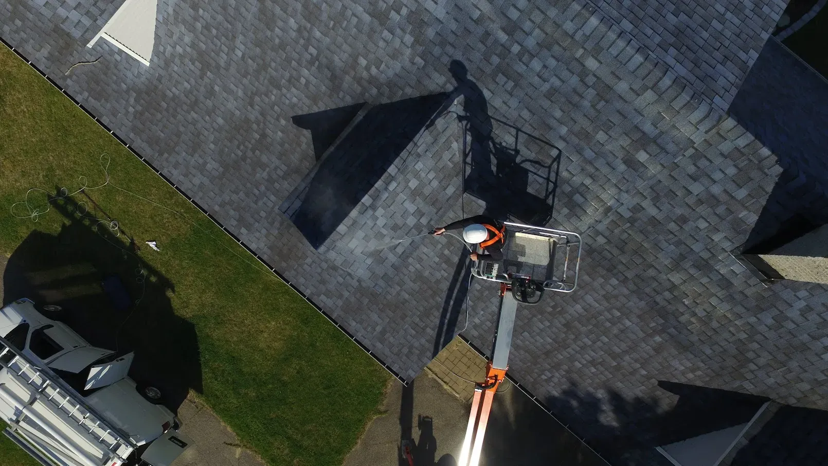 Professional applying GoNano treatment to asphalt shingles on a residential roof